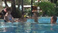 Europeans happy family playing with a baby in a swimming pool. young girl and the woman throwing the baby small ball in t