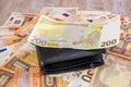 200 euros and a black men`s wallet on a background of euro banknotes. Much money. Cash background.