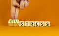 Eustress or stress symbol. Psychologist turns cubes and changes the concept word Eustress to Stress. Beautiful orange table orange