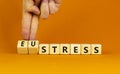 Eustress or stress symbol. Psychologist turns cubes and changes the concept word Eustress to Stress. Beautiful orange table orange