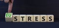 Eustress or stress symbol. Turned the wooden cube and changed the concept word Eustress to Stress. Beautiful grey table grey