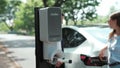 EV car recharging electricity for battery by lovey couple on road trip. Exalt