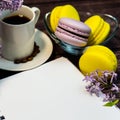 An even row of multicolored macaroons, a small alarm clock, a cup of coffee and a notebook on a wooden background. Royalty Free Stock Photo