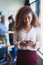 Even smartphones are used to manage business. a young woman using a mobile phone with her team in the background of a Royalty Free Stock Photo