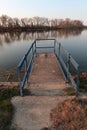 Evenig view of concrete molo on dam of large artigicial fish pond with spillway channel hatch and railing.