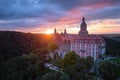 An evening aerial view of the red sunlit Ksiaz Castle, Schloss FÃ¼rstenstein, a beautiful castle standing on a rock