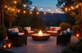 Evening backyard patio features fire pit seating area with string lights illuminating sofas and chairs. Cozy outdoor lounge space Royalty Free Stock Photo