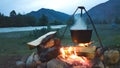 Evening campfire during a camping trip. Cauldron on a burning fire. The tent is far away. Cozy Hiking evening of travelers Royalty Free Stock Photo