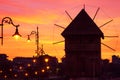 Evening city landscape - view of the silhouettes of the wooden windmill and street lamps on the embankment of Nessebar before the Royalty Free Stock Photo