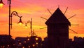 Evening city landscape - view of the silhouettes of the wooden windmill and street lamps on the embankment of Nessebar before the Royalty Free Stock Photo