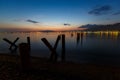 Evening city, the sea is beautifully reflected city lights. Mountains and sunset in the background.