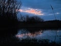 Dark evening clouds with orange glow over a marsh in the flemish countryside Royalty Free Stock Photo