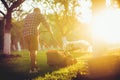 Evening details of industrial gardening and landscaping. Caucasian Gardener working with lawnmower and cutting grass