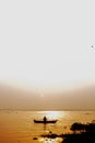 Evening golden sunset time, a fisherman fishing on the seaside on a boat Royalty Free Stock Photo