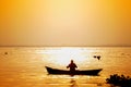 Evening golden sunset time, a fisherman fishing on the seaside on a boat Royalty Free Stock Photo