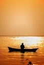 Evening golden sunset time, a fisherman fishing on the seaside on a boat Royalty Free Stock Photo