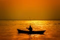 Evening golden sunset time, a fisherman fishing on the seaside on a boat Royalty Free Stock Photo