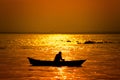 Evening golden sunset time, a fisherman fishing on the seaside on a boat Royalty Free Stock Photo