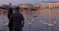 Evening guy hugs the girl on river bank. They look water, swans are swimming. Royalty Free Stock Photo