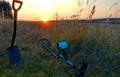 evening landscape. field, trees, grass, sunset, metal detector and search shovel in the foreground. Royalty Free Stock Photo