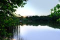 evening landscape with forest lake, river, line of trees is reflected in water, blue sky is reflected in calm water surface, Royalty Free Stock Photo