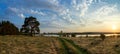 Evening landscape with lush pine tree on the banks of the river and a dirt road Royalty Free Stock Photo