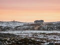 Evening polar landscape with an old dilapidated house on a rocky shore. Winter Teriberka