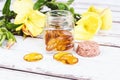 Evening primrose oil capsules in bottle, soft gels, Oenothera biennis plant on wooden table Royalty Free Stock Photo