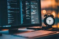 Evening programming session with a computer displaying code and a clock showing the time Royalty Free Stock Photo