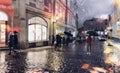 Evening rainy urban street people walk with umbreellas city bokeh blurred light wet pavement medieval houses i