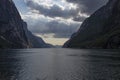 Evening shot of beautiful fjord valley, surrounded by mountains, cloudy blue skies