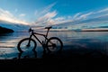 Evening silhouette of a mountain bike on the lake with a beautiful sunset