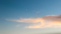 Evening sky with moon and clouds. Golden warm pastel clouds. sunset giving Golden colors to the sky. blue sky with a white moon in