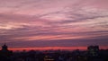 The evening sky over the roofs of houses in the city. Beautiful fiery sunset, clouds and light in the windows of houses