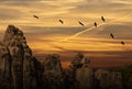 Evening sky with the silhouettes of migrating gray geese in the sky above a frightening rock formation Royalty Free Stock Photo