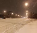 In the evening, a snowstorm beautifully sweeps the city roads with snow, illuminated by bright lanterns Royalty Free Stock Photo