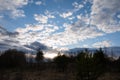 Evening spring blue sky with white clouds. Dark silhouettes of trees and shrubs. Royalty Free Stock Photo