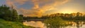 Evening spring landscape. panoramic view of the river with a hilly grassy shore against a cloudy sky with a glow from sunset Royalty Free Stock Photo