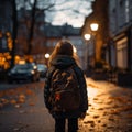 Evening street ambiance, cute primary student with backpack, back view