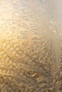 Evening sun and bright blue sky through the frost pattern on the window. Ice pattern and sunlight on winter glass Royalty Free Stock Photo