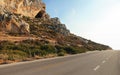 Evening sun shines on sharp rocks by the asphalt road - typical scenery on Karpasia peninsula in northern Cyprus