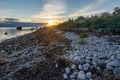 Evening sunlight on coast, pink clouds, blue sky reflection on water. Beach in summer. Seaside natural environment. Royalty Free Stock Photo