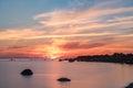 Evening sunlight on coast, pink clouds, blue sky reflection on water. Beach in summer. Seaside natural environment. Royalty Free Stock Photo