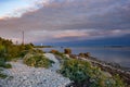 Evening sunlight on coast, pink clouds, blue sky reflection on water. Beach in summer. Seaside natural environment. Royalty Free Stock Photo