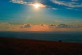 Evening sunset landscape over the mountain valley. Bright evening sun and orange clouds over low mountains, panorama. Royalty Free Stock Photo