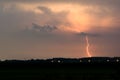 Red colored lightning bolt strikes from a distant thunderstorm Royalty Free Stock Photo