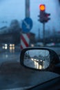 Evening traffic jam in side rear-view mirror with red traffic lights