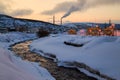 Evening urban landscape with a small river, buildings, hills and fuming pipes Royalty Free Stock Photo