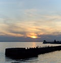 Evening view of the embankment, unfinished pier and the reflection of the setting sun and sky in the surface of the river.