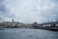 Evening view of Galata tower district, buildings, bridge with people fishing and Bosporus sea water with boats, seagulls and cloud